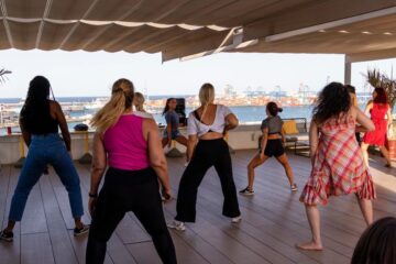 Frauen tanzen auf Terrasse mit Blick auf den Hafen