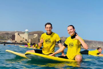 Junger Mann und junge Frau auf ihren Surfbrettern lächeln in die Kamera