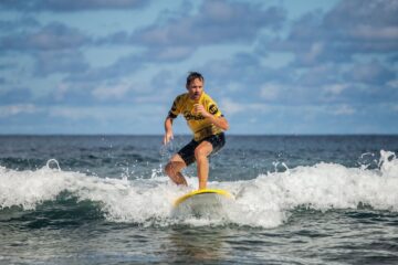 Mann auf Surfbrett surft mit der Welle