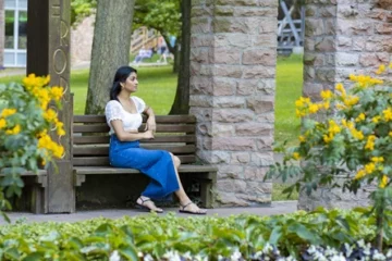 Frau sitzt auf Bank bei Blumenbeeten