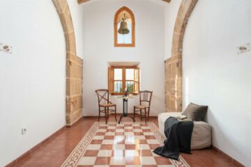 Stühle mit Tisch unter Fenster und Glocke und Sofa mit Decke