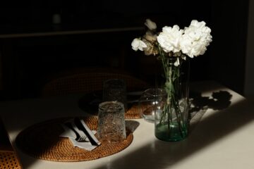 Vase mit weißen Blumen, Platzteller aus Bast