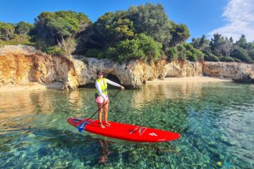 Frau mit SUP in Bucht mit klarem Wasser