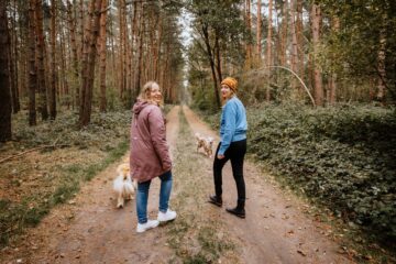 Zwei Frauen mit Hunden auf Waldweg