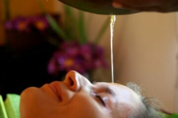 Frau die mit einem ayurvedischen Stirn-Öl-Guss behandelt wird.