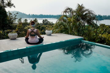 Frau beim Meditieren und Yoga in der Natur neben dem Pool