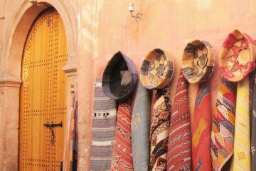 Verschiedene traditionelle Gewänder und Hüte, die an einer Wand in Marrakesch hängen