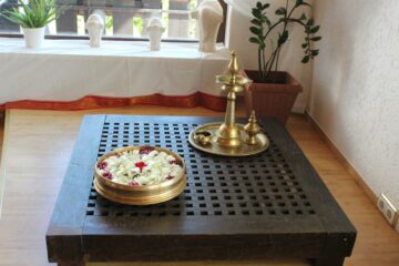 Indische Messinggegenstände auf einem kleinen Tisch zusammen mit einer Schale mit Blumen