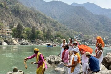 Ein indischer Priester bei einer Zeremonie am Ganges Fluss mit einer kleinen Gruppe von Menschen.
