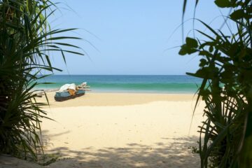 Sandstrand mit türkisfarbenen Meer und einem Holzboot