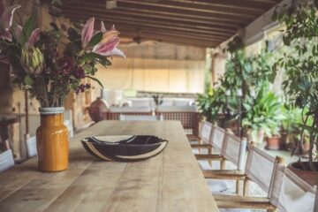 Holztisch mit Blumenvase und einem Teller