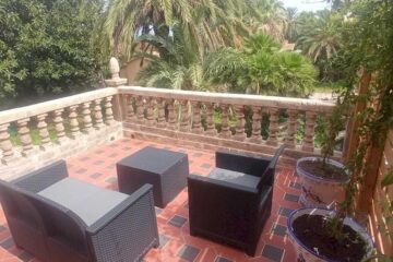 Balkon mit zwei Sesseln und Tisch mit Blick auf einen tropischen Garten