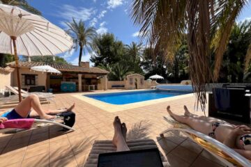 Drei Menschen auf Liegestühlen an einem Pool