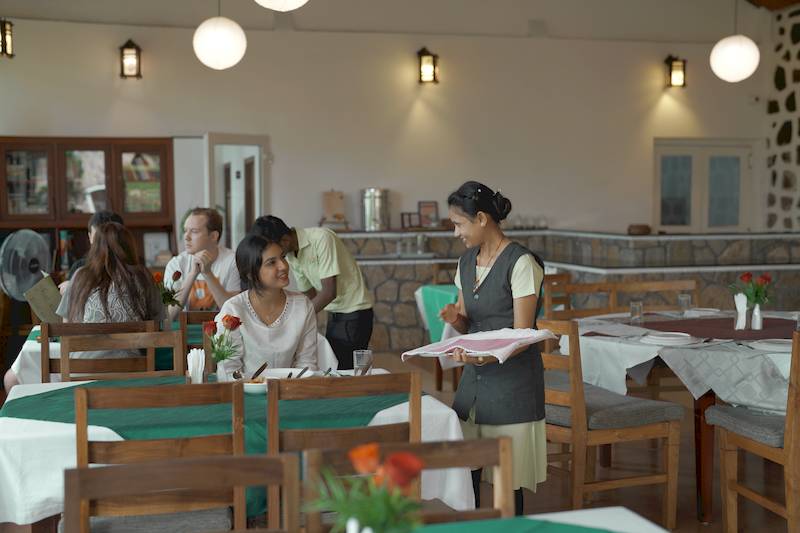 Mehrere Menschen in einem Speisesaal mit einer Mitarbeiterin des Hotels in Indien