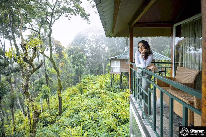 Frau auf einem Balkon einer kleinen Hütte in einem Wald in Indien